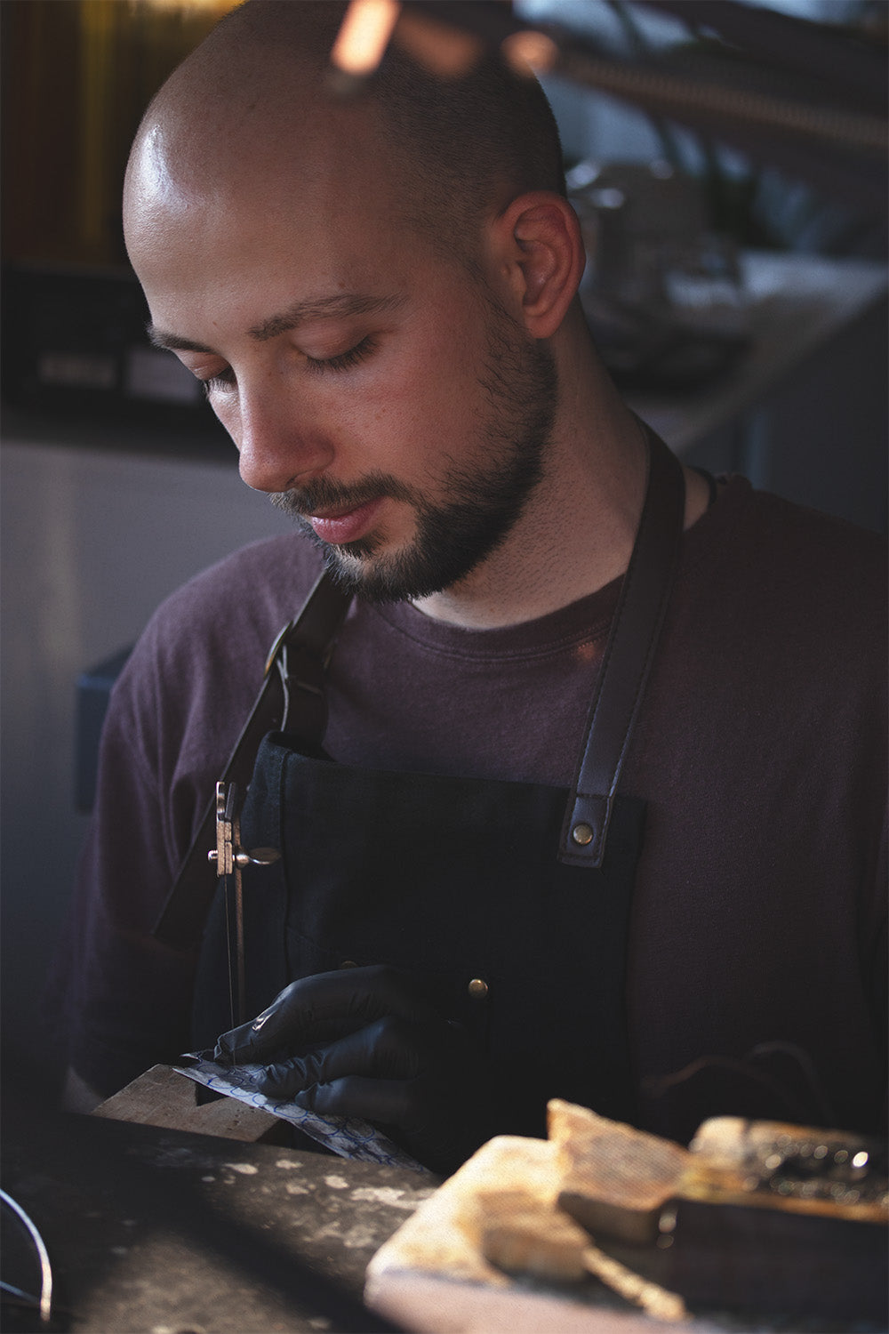 Man wearing a black apron in a workshop setting creating a ring in Lisbon.