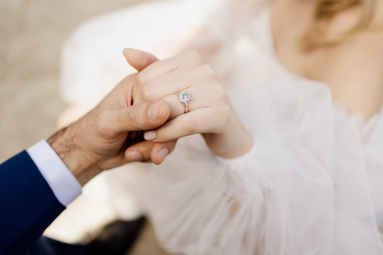 Man doing proposal to woman holding her hand with engagement ring.