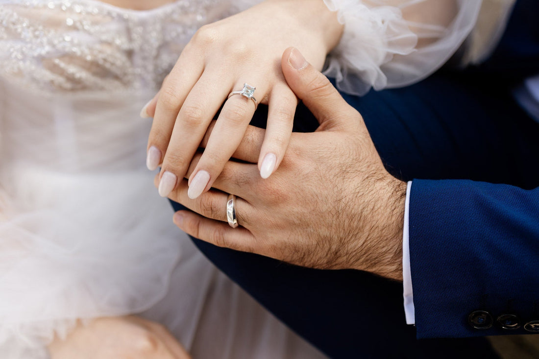 A couple's hands showing their custom wedding rings: a white gold diamond engagement ring and a unique men's wedding band from Amare Jewelry, Lisbon.