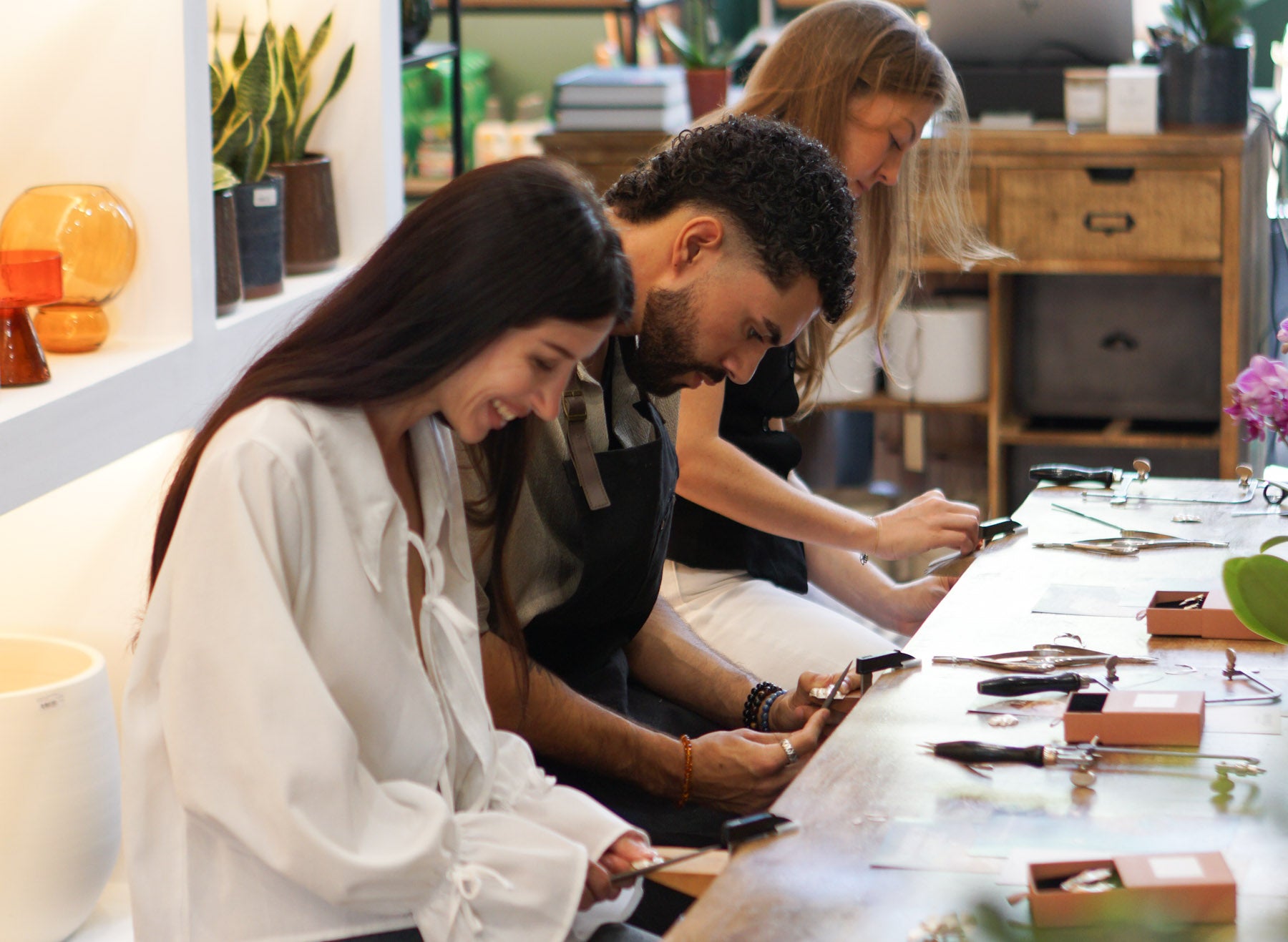 A diverse group of people enjoying a fun, creative silver jewelry making workshop at the Amaré artisan studio in Lisbon.